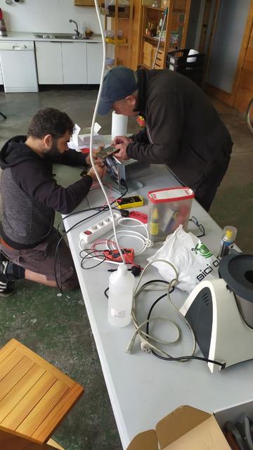 Plano medio con duas persoas reparando en mesa con distintos aparatos e ferramentas