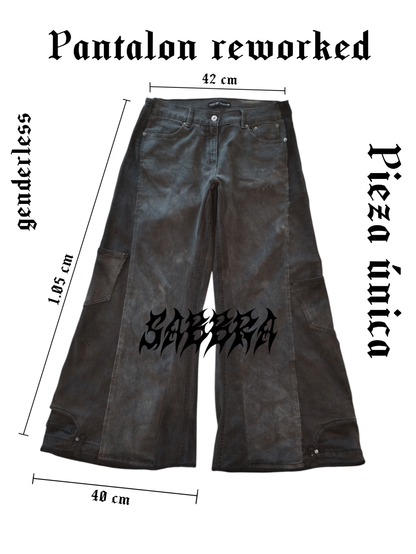 La imagen de fondo blanco muestra un pantalón en plano. El pantalón está hecho a partir de dos pantalones ajustados, dando así una bota muy ancha, es un jean negro desgastado, a los bordes tienen las medidas que son: Pretina: 42cm, Largo: 105cm, Bota: 40cm. A los costados y arriba tiene escrito en letra gótica lo siguiente:
Pantalón reworked
Pieza única
genderless
sabbra