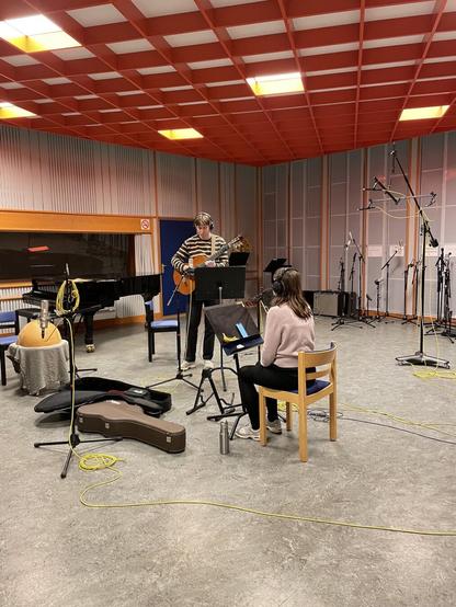 A guitarist and a vocalist in a studio
