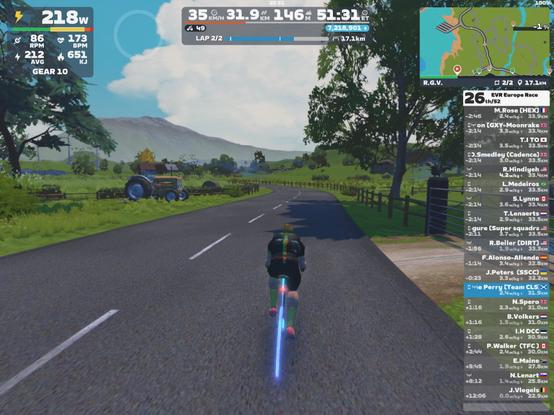Screenshot from Zwift with a cyclist in Team CLS attire riding past an old tractor in front of the Ven Top mountain.