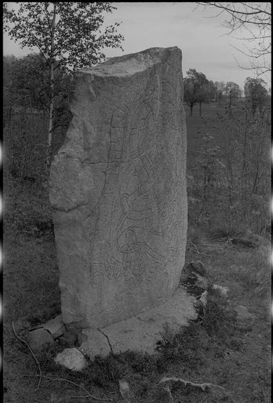 A black and white photo of a runestone on a overcast day.