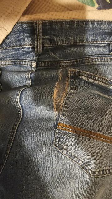 Faded blue jeans, butt quadrant,  with a rip north to south covering the rear right pocket