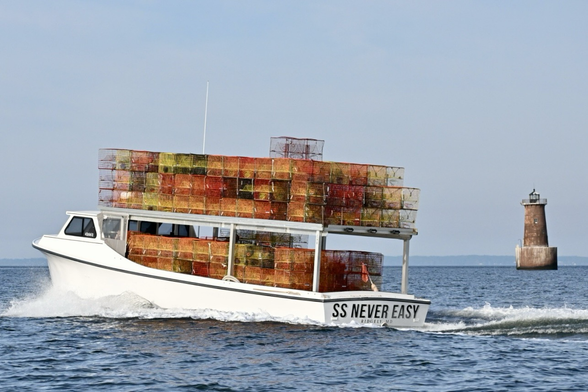 Crab boat piled high with colorful crab pots. The Bloody Point lighthouse in the background.