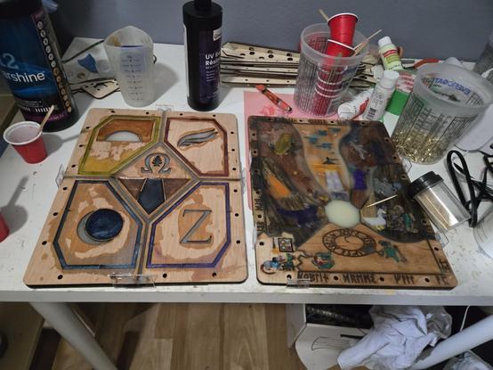 Chaotic scene of 2 book covers slather Ed unevenly in resin at various states of fullness and curing