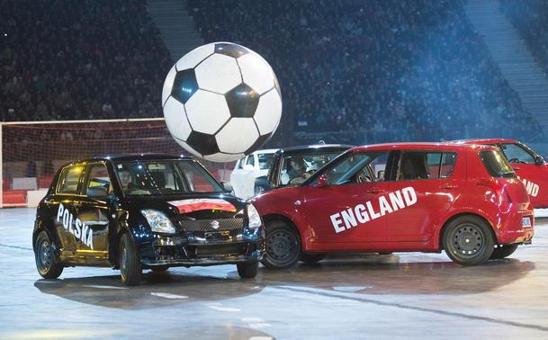 A football match with a giant soft football and two real-life cars