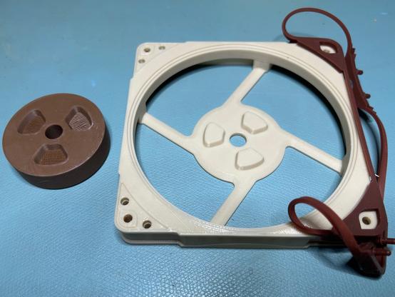 The same Noctua fan.  The center hub has been lifted out to show its alignment pins.  The rubber surround has been peeled back from two corners to show the structure underneath.