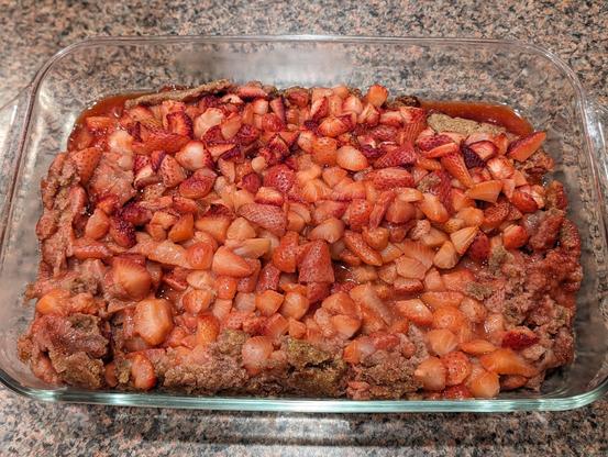 unbaked crostata with extremely short walls, loaded with about 4x the appropriate amount of cut strawberries, sitting on a thin silicon baking sheet in a quarter sheet pan
