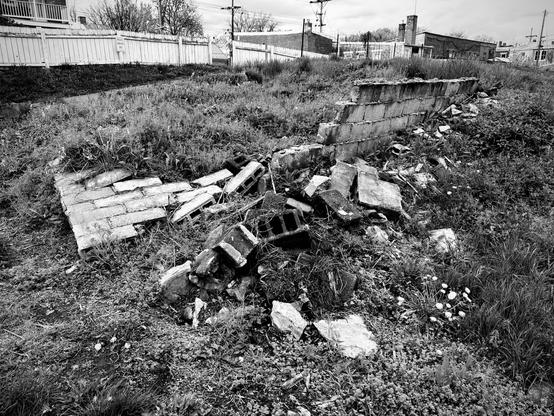 Black and white photo of a partially buried and collapsed cinder block wall