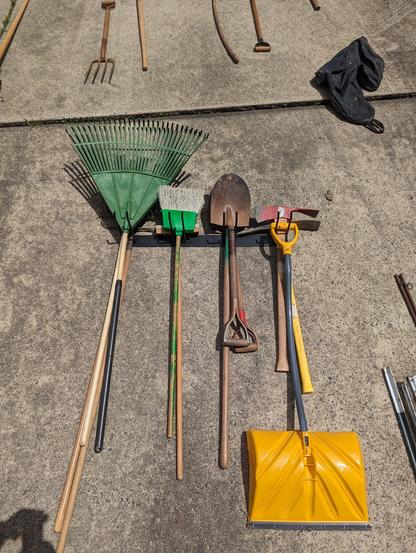 Figuring out how best to organize the yard tools in the tool rack while it's lying on the driveway. That way we could know how it needed to be positioned on the wall.
You can also see extra tools around it that were ultimately given away.