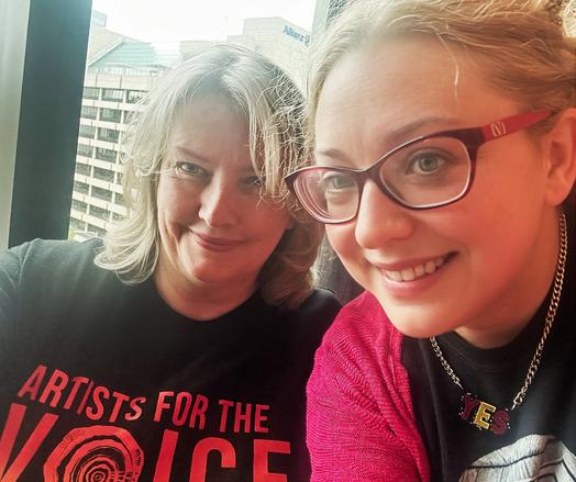 Tammy Franks in an “Artists for the Voice” t-shirt, sits next to Van Badham who herself wears a “YES” necklace. They are both smiling.