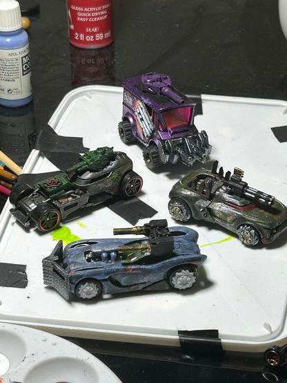 four modified hotwheels that have 3d printed weapons on them and armour they look like twisted metal meets mad max. they cary in color and sizes from an iscream truck with a tak turret to a scifi with carved spikes all over it
