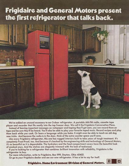 Magazine ad from 1974 by Frigidaire advertising a cherry red refrigerator with built-in AM/FM radio and cassette player. A white dog with black spots stares up at it as though listening to its owners voice.