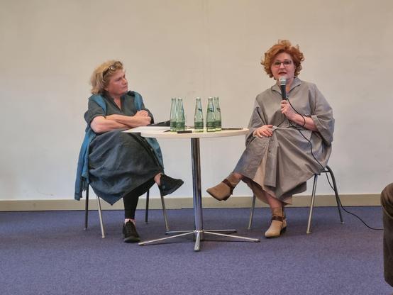 Zwei Frauen mit Mikro am runden Tisch