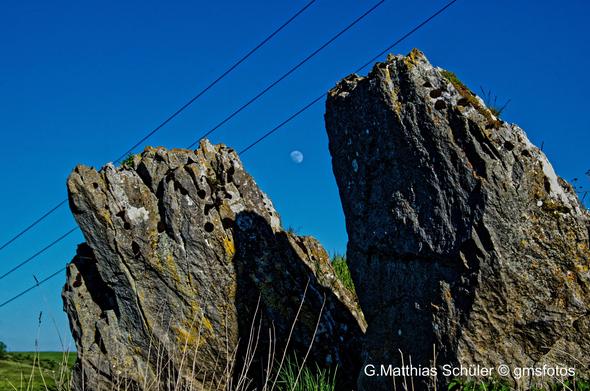 Der Mond zwischen 2 Felsen und darüber einen Stromleitung