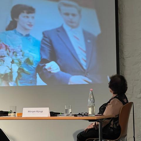 Die Zeitzeugin Sonja Mühlberger schaut bei der Projektpräsentation auf eine Projektion ihres Hochzeitsfotos.