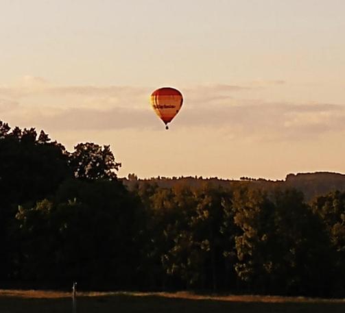 Heißluftballon schwebt am Abendhimmel über die Wälder der sächsischen Schweiz.