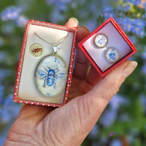 Halsschmuck in ovalem Edelstahl Anhänger und runde Ohrstecker mit winzigen handgemalten blauen bienenmotiven