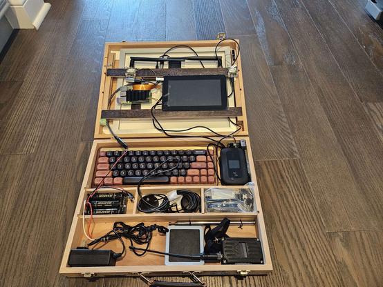 Cyberdeck built by user var_x consisting of a wooden box with all the components placed or strapped in place with no covering, wires crossing every part of it