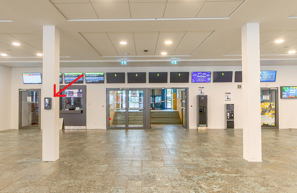 Das Foto zeigt eine Ansicht aus dem Foyer der Mensa im Adenauerring. Oben an der Decke sind Fluchtwegbeschilderungen zu sehen, links und recht im Bild die Säulen des Foyers. An der linken Säule ist ein warzer Kasten angebracht, um den es im Post geht. Es zeigt ein eingezeichneter dicker roter Pfeil darauf.
Hinter der rechten Säule sind die Aufwerter neben dem [pizza]werk zu erkennen.

Ursprungsbild stammt vom "360°-Rundgang auf sw-ka.de