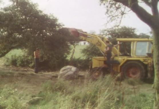 Screengrab from Stigma (1977) where some workmen are about to lift a giant stone with a JCB and release an ancient curse.