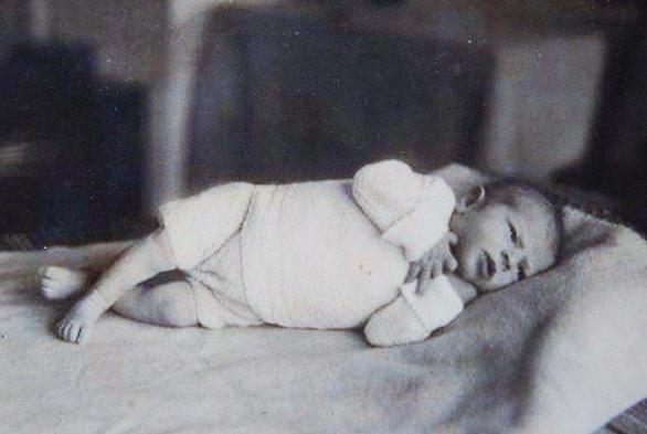 A baby girl lying on a bed.