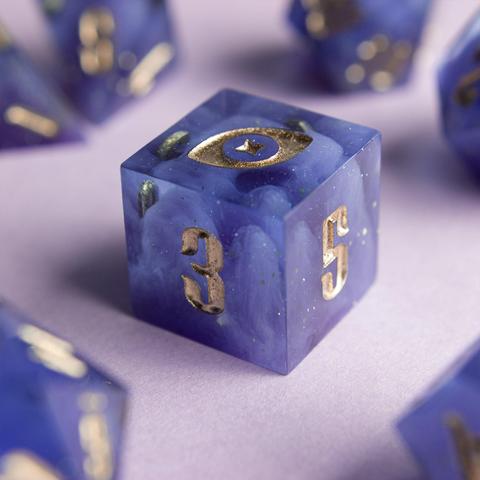 Zu sehen ist ein D6 in transparentem Violet. In inneren sieht man wallende Wolkenschwaden die von Glitzer umtanzt werden.

Die Nummern wurden mit Gold geinked. Die Zahl 6 wurde durch mein Logo, ein Auge mit Stern, ausgetauscht.
