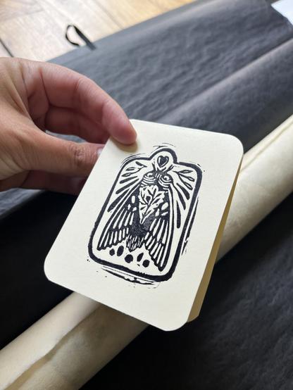 Petite carte tamponnée en noir, représentant un insecte imaginaire envoyant un coeur.