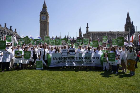 100+ scientists in front of UK Parliament buildings, banner reads 'Bringing Science to Politics for Climate, Nature & Survival'