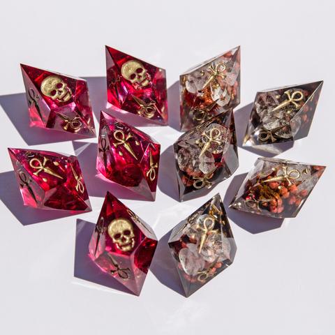 Auch hier ist das komplette Set zu sehen. Hunger Würfel in Blutrot, die normalen Würfel im Blüten-Stil. Die Würfel haben allesamt Antik-Goldene Symbole und liegen auf weißem Untergrund.