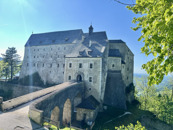 Burg Altpernstein mit Zugangsbrücke vorne, der Burg hinten und grünen Blättern rechts im Bild