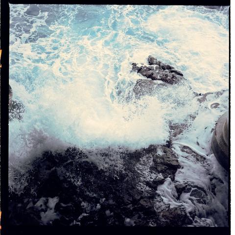 A photograph capturing an energetic ocean scene where waves are crashing on rocks, highlighting the force of nature in contrast to the calmness beneath the water's surface.