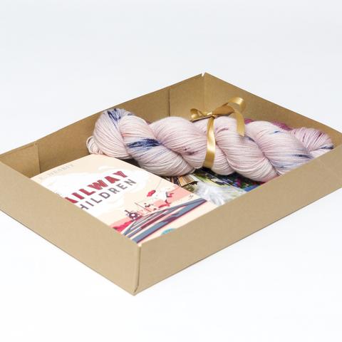 Picture shows an open A4 box containing a sock set of yarn and a copy of The Railway Children book. The rest of the box contents is obscured.