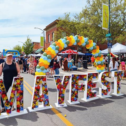 Rebecca Long standing behind the downtown Cheney, Washington Mayfest sign