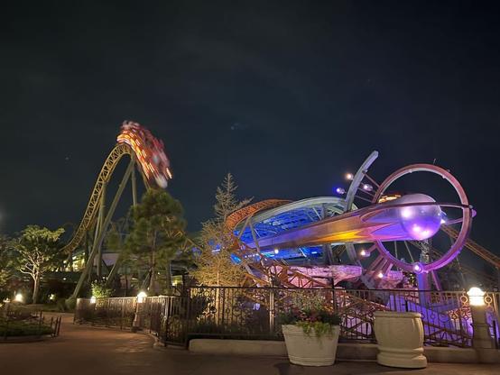 A roller coaster crests a hill at night in Epic Universe.