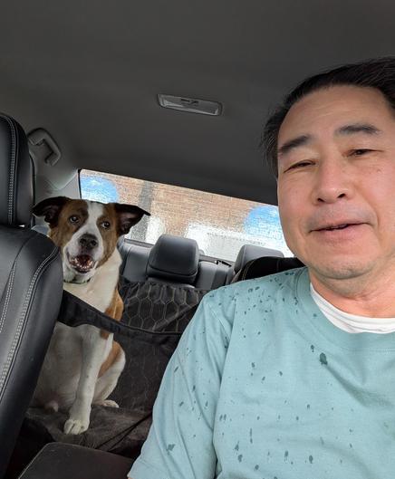 A selfie in a car. Me the driver on the right, a white and brown dog sitting on the rear seat on the left