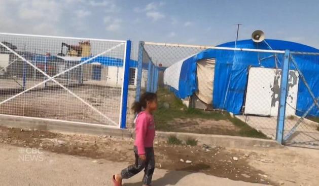 Une enfant au milieu d’un camp.