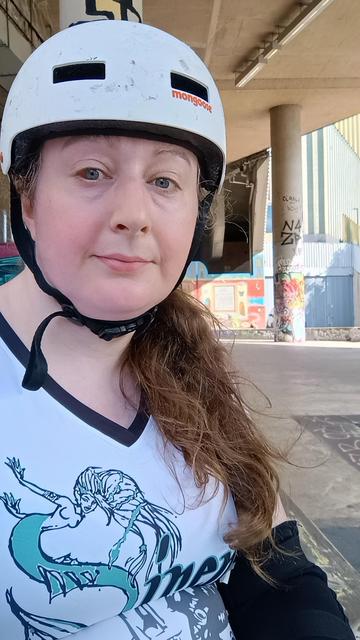 A picture of me in roller derby gear at the Tram Line Spot public skate park in Nottingham. I'm wearing my Southland Sirens white away jersey.