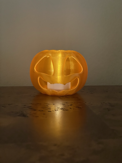 Photo of an orange semitransparent 3d printed jack-o’-lantern. It is lit from the inside by an LED tea light.