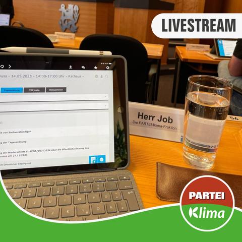 Zu sehen ist eine Nahaufnahme des Tisches von Stefan Job (Klimaliste) im Plenarsaal des Düsseldorfer Rathauses. Im Fokus ist der geöffnete Laptop und ein Glas Wasser.