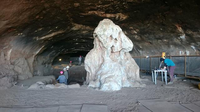 Eine hallenartige Höhle, in der mehrere Personen arbeiten