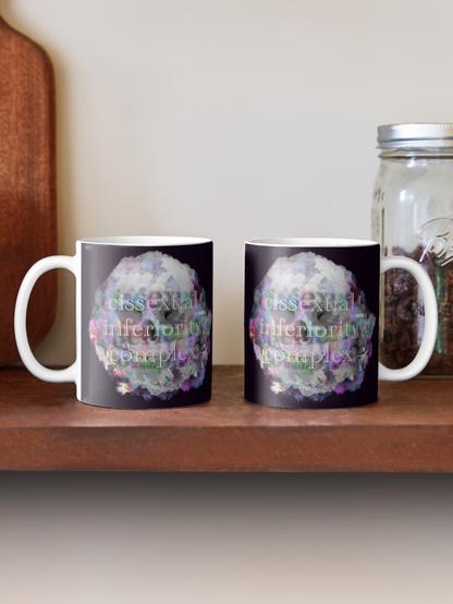 two cups with the same design, presented to show front and back. the design features a skull and glitchy trans pride colors in neon. overlayed text reads "cissexual inferiority complex"