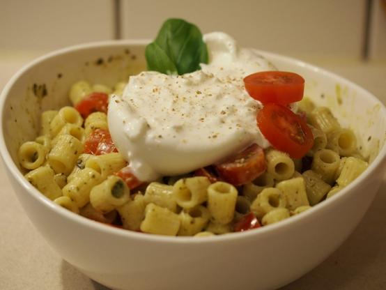 Pasta mit Pesto und Burrata garniert mit frisch gemahlenen Pfeffer, Tomatenscheiben und einem Blatt frischem Basilikum