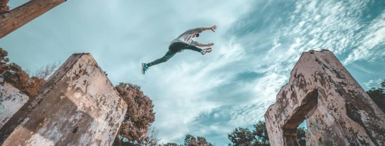 Picture of a parkour enthusiast jumping from one crumbling wall to another.