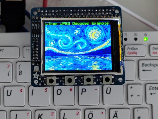 Photo of a rpi400 computer with a 2.2" LCD attached showing a photo of artwork my daughter created.