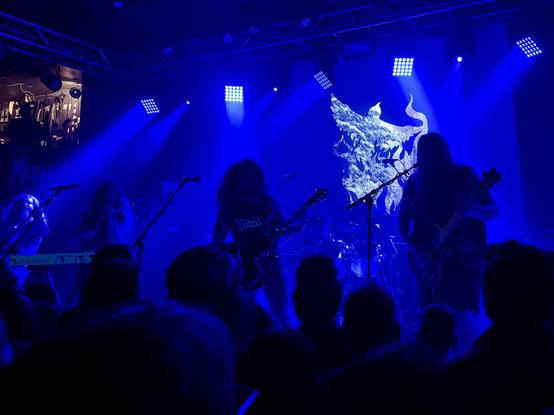 Blue on blue stage shot, five long haired pagans holding a very loud service.
