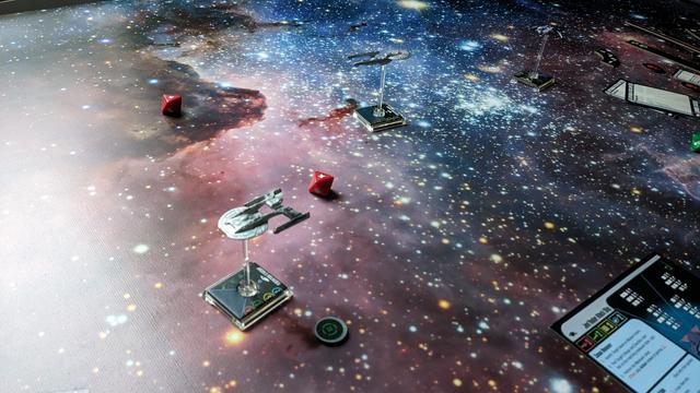 A big space mat with a federal starship flying towards the camera. In the right corner is a bluish paper card.