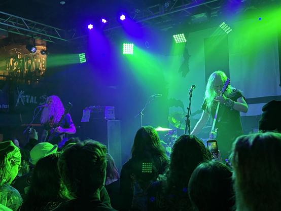 Two guitar players with long white hair bathed in purple and green light. Wizards!