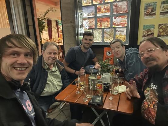 Ein Tisch im Außenbereich einer Gaststätte. Darauf überwiegend leere Gläser und 5 Personen. Auf dem Tisch steht ein Wimpel der Piratenpartei.