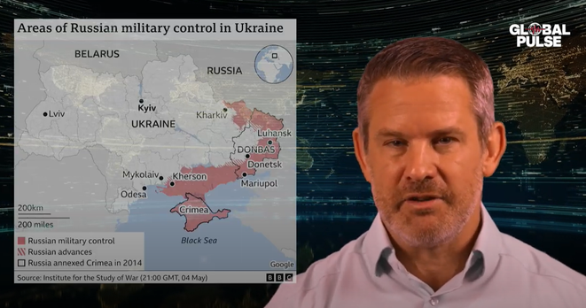 Screenshot aus einer "Global Pulse"-Sendung. Rechts steht ein Mann vor einer digitalen Weltkarte. Links zeigt eine eingeblendete Karte die militärische Kontrolle Russlands in der Ukraine. In rot sind Gebiete wie Donezk, Luhansk, Mariupol, Cherson und die Krim markiert. Quelle: BBC / Institute for the Study of War.

Screenshot from a "Global Pulse" segment. On the right, a man stands in front of a digital world map. On the left, a map shows areas under Russian military control in Ukraine, including Donetsk, Luhansk, Mariupol, Kherson, and Crimea in red. Source: BBC / Institute for the Study of War.