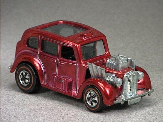 Released in 1971, Spectraflame Magenta Cockney Cab of 1971 Hot Wheels with Redline wheels. Notes: Metal engine block, no door on left side. Tampo: Sticker with Union Jack and 'Cockney Cab' on rear. Packaging: 1971 Blister. Metal Body, Metal Base. Made in Hong Kong. Scarcity: 6/10